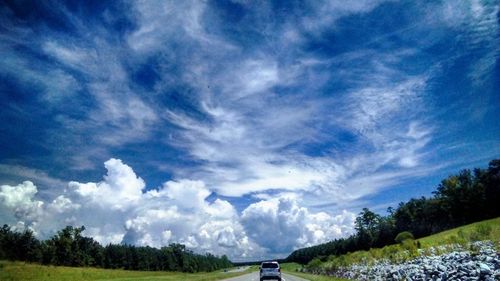 Cars on road amidst field against sky