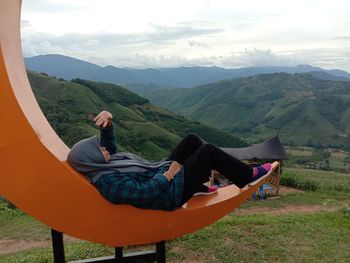 Women relaxing on mountains against sky