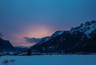 Scenic view of snowcapped mountains against sky at sunset