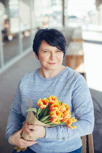 Portrait of woman holding ice cream standing outdoors