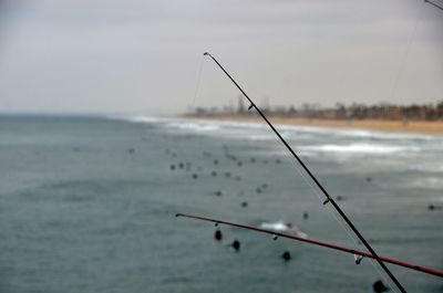 Fishing rod on sea shore against sky