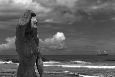 Close-up of statue by sea against sky