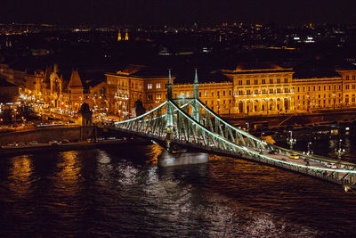 Illuminated bridge over river at night