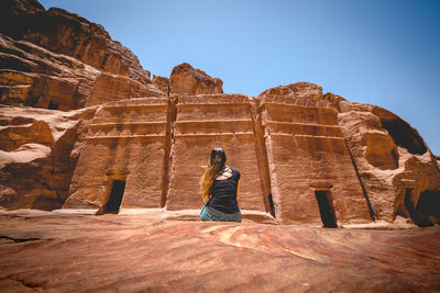 Rear view of woman sitting on rock