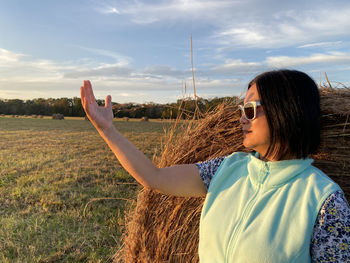 Close-up of woman shielding eyes standing at farm