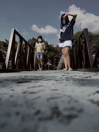 Full length of woman with arms raised against sky