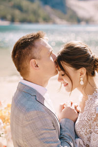 Smiling bridegroom embracing while standing outdoors