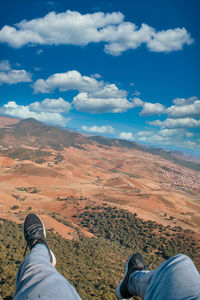 Low section of man on mountain against sky