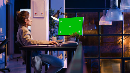 Side view of young woman using laptop at table