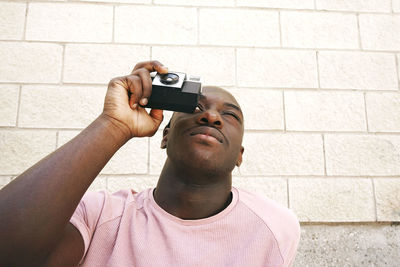 Man photographing through camera against wall