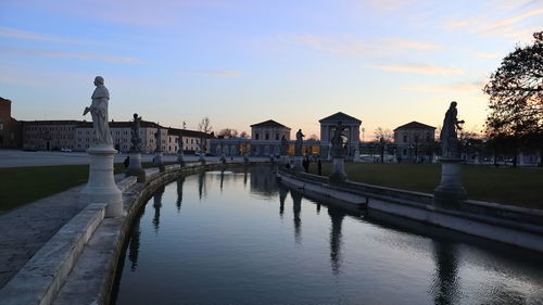 Pier over river by buildings in city against sky