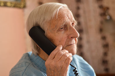 Close-up of a 90-year-old elderly retired woman who is talking smiling on the phone. selective focus