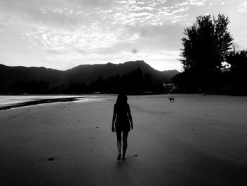 Rear view of woman walking on street against sky