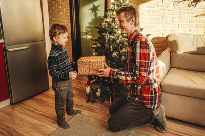 Smiling father giving gift to son at home
