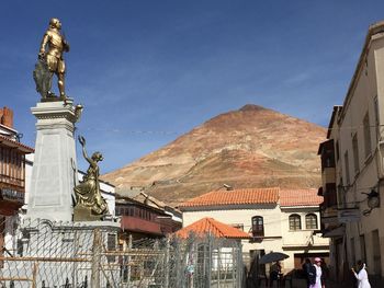 Statue in city against sky