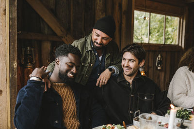 Smiling man talking to male friends at dinner party