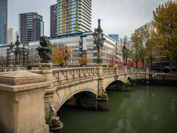 Arch bridge over river by buildings against sky