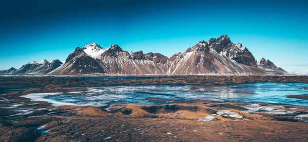 Scenic view of snowcapped mountains against blue sky