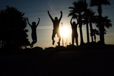 Silhouette of people jumping at sunset