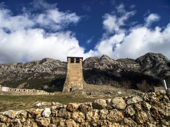 Built structure on rocky mountain against sky