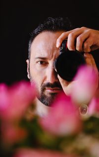 Close-up portrait of man holding pink camera