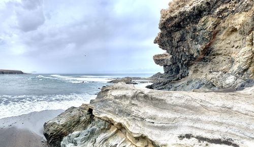 Rock formation on beach against sky