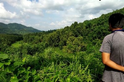 Rear view of man standing by plants against sky