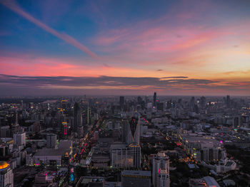 High angle view of illuminated city buildings against sky during sunset