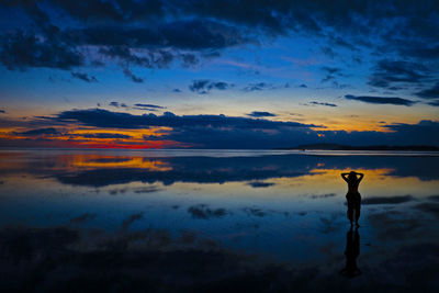 Silhouette man standing by sea against sky during sunset