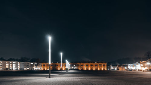 Illuminated street against sky at night