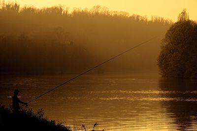 Fishing rod over sea against sky during sunset