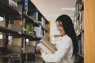 Side view of a young woman reading book