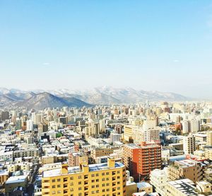 High angle view of cityscape by mountain against sky