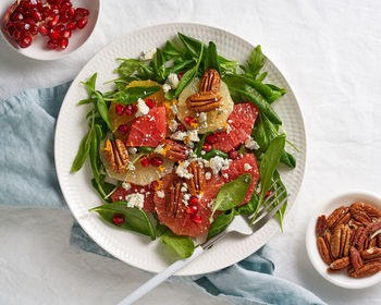 Fruits citrus salad with nuts, green lettuce leaves. balanced food. spinach with orange, grapefruit