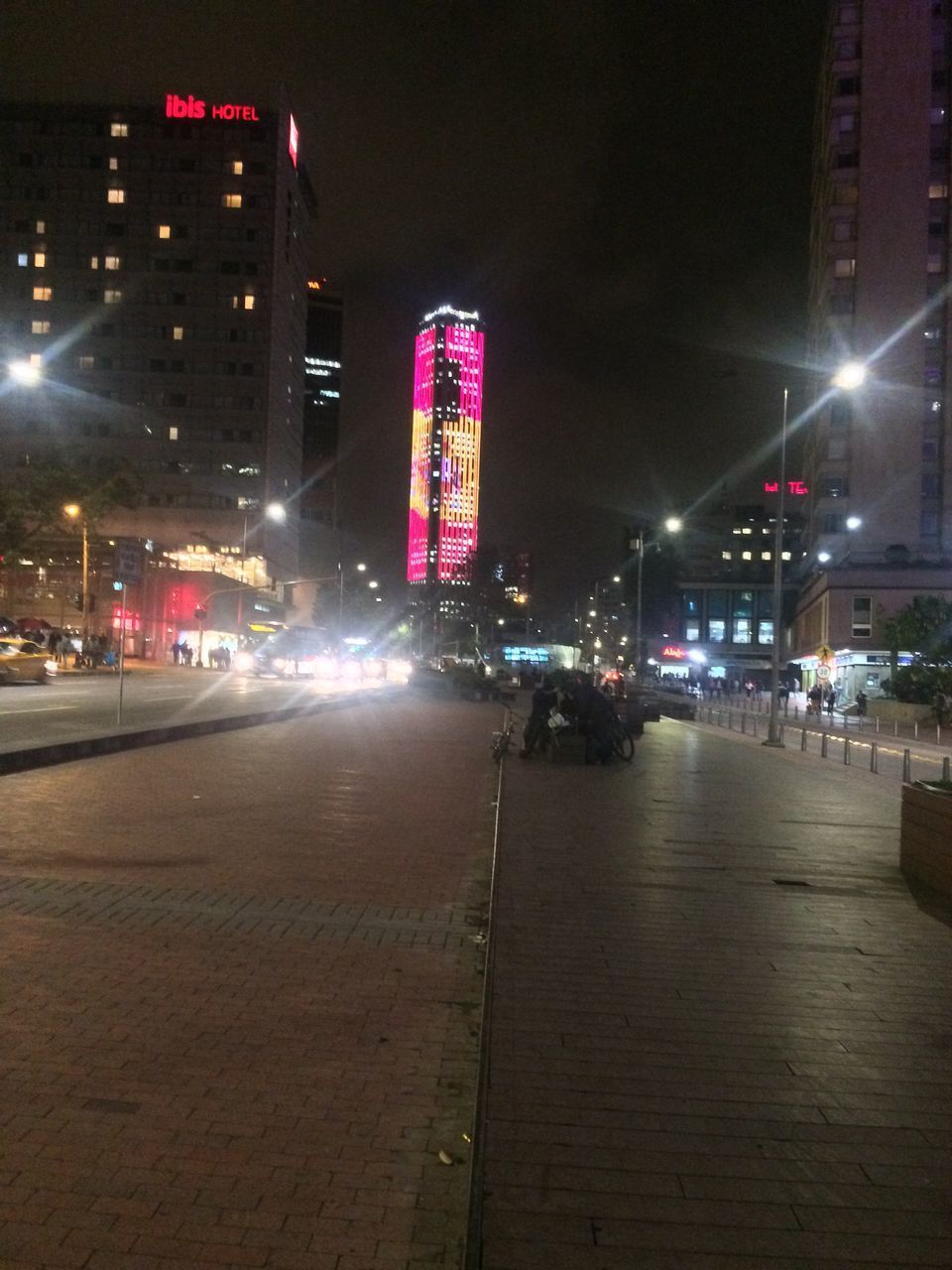 CITY STREET BY ILLUMINATED BUILDINGS AT NIGHT