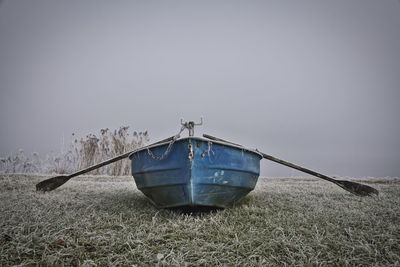 Boat moored on field against clear sky