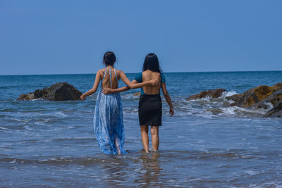 Rear view of woman standing in sea against clear sky