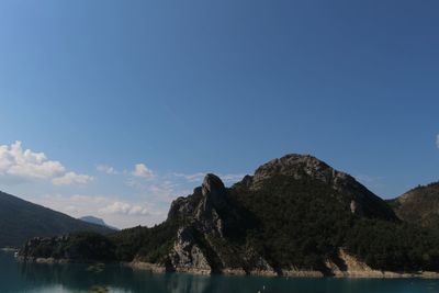 Scenic view of lake and mountains against clear blue sky