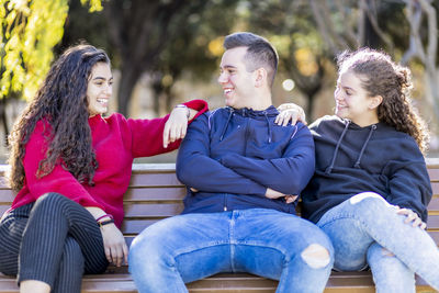 Happy teenage friends sitting in park