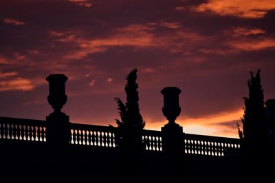 Silhouette railing against orange sky