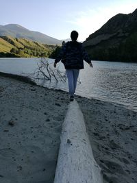 Young woman walking on driftwood at riverbank