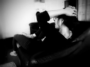 Midsection of young woman sitting on sofa