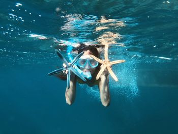 Portrait of woman holding starfish while snorkeling in sea