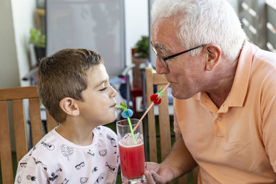 Grandson and grandfather drinking juice at home