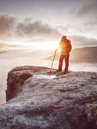 Woman hiker on extreme trail in rocks enjoy amazing view into misty valley. hiker enjoy silent rocks