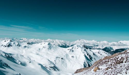 Scenic view of snowcapped mountains against blue sky