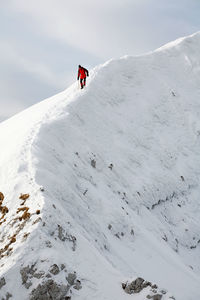 Low angle view of mountaineer climbing snowcapped mountain against sky