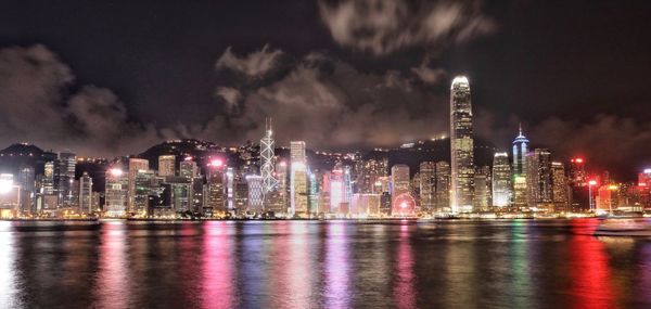 Illuminated modern buildings in city against sky at night