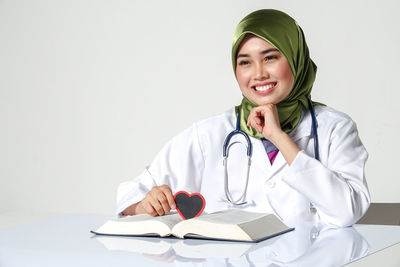 Portrait of smiling young woman sitting on table