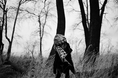 Woman standing against trees in forest